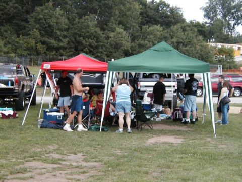 1994 Ford Bronco - A gathering of people under tents with several vehicles visible in the background on a grassy field.