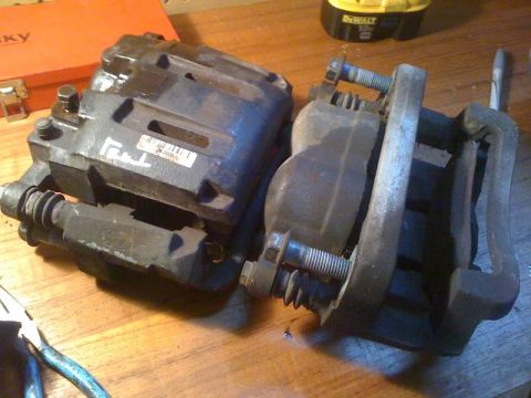 2007 Ford Mustang - Two brake calipers, one with a visible Ford logo, are shown on a workbench.