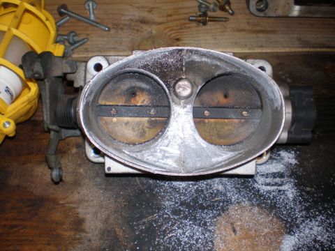 2007 Ford Mustang - A used throttle body sits on a workbench, surrounded by metal shavings.