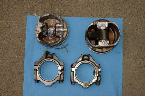 2007 Ford Mustang - Two severely damaged pistons and two connecting rods are displayed on a blue shop towel, indicating significant engine failure.