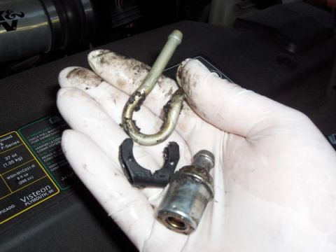 2007 Ford Mustang - Removed fuel line components are held in a gloved hand, showing signs of wear and tear.