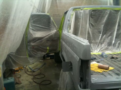 1993 Ford Bronco - Two vehicles are being prepped for painting in a booth, with one vehicle's side profile visible.