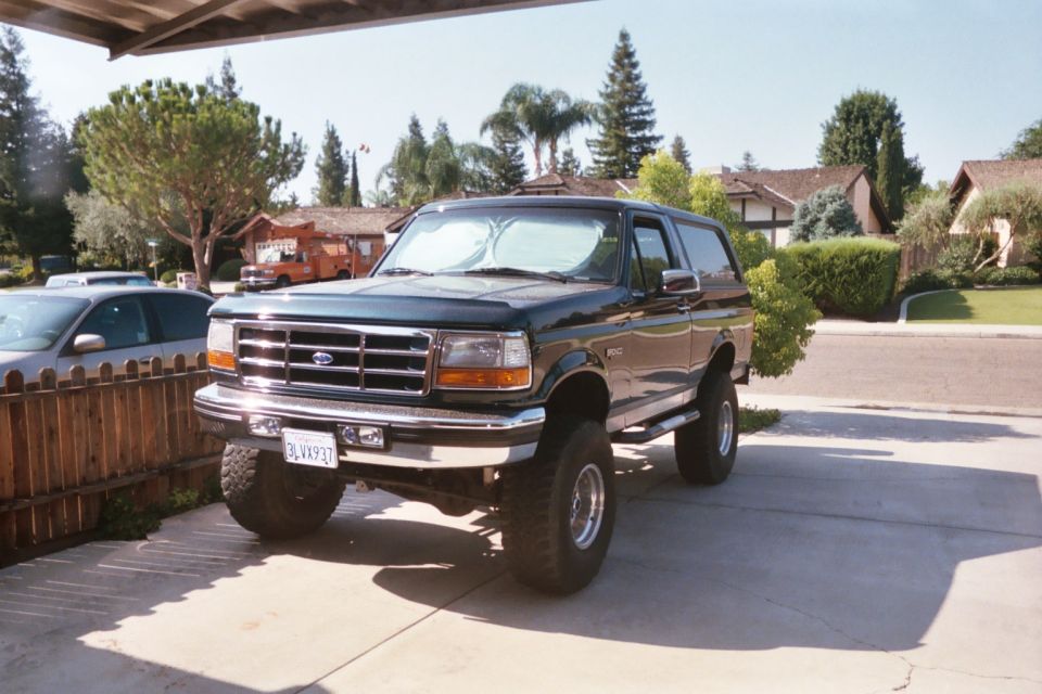 Black lifted full-size Ford Bronco parked under a carport in a residential driveway