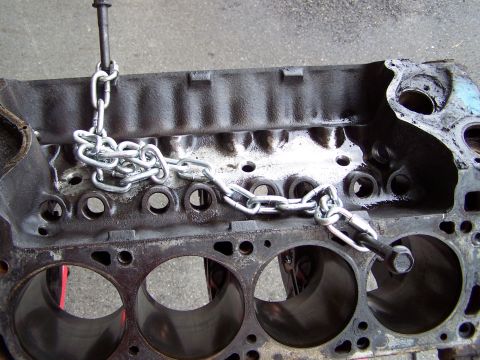 1973 Ford Ranchero - Engine block being lifted by a chain hoist, showing cylinder bores and casting details.