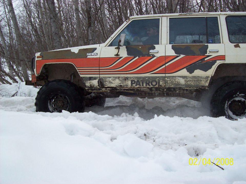 White Nissan Patrol with orange stripes driving through snow