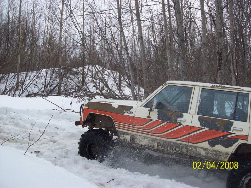 Off-road vehicle with "PATROL" text on its side, driving through snow