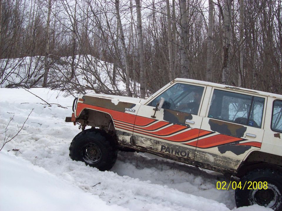 White and orange 4x4 with 'PATROL' text driving in snow