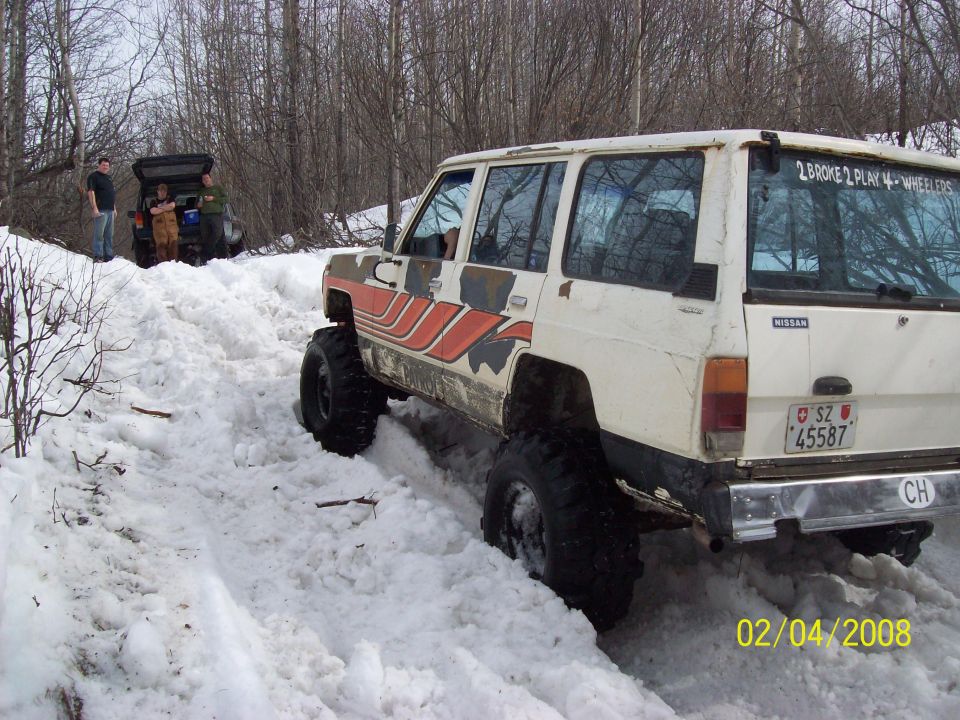 White Nissan Patrol with off-road tires in snow, rear view