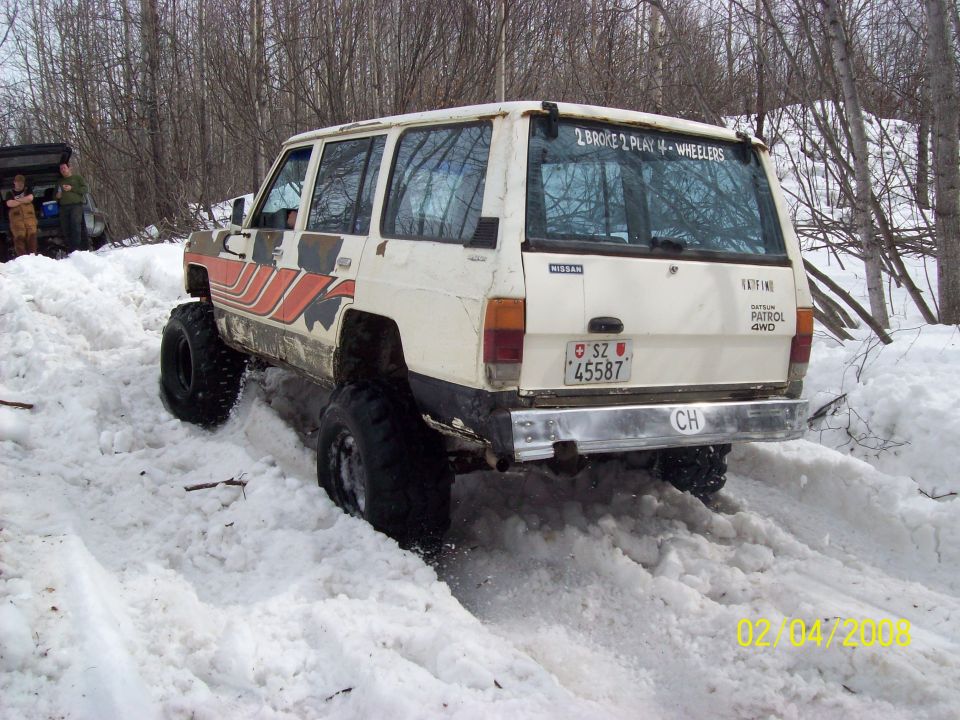 Nissan Patrol 4x4 with big tires driving in snow, another vehicle in background