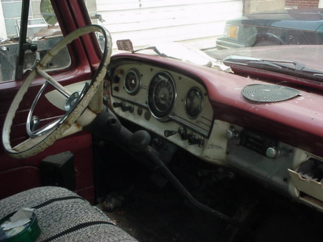 Weathered early-1960s Ford pickup dash with three-pod gauges and white wheel