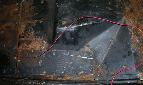 1979 Ford Bronco - The interior floor pan shows significant rust and a red wire running across it.