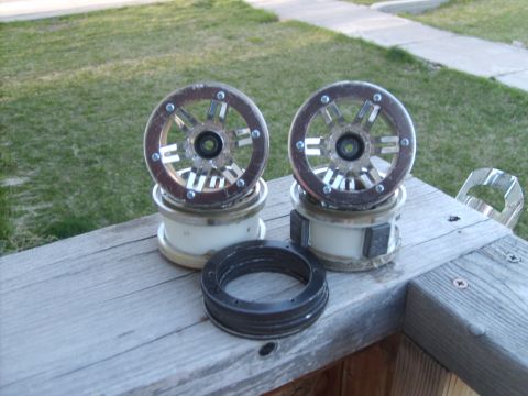 1989 Ford Bronco - Two car wheel hubs and brake rotors are displayed on a wooden surface, with grass and a sidewalk in the background.