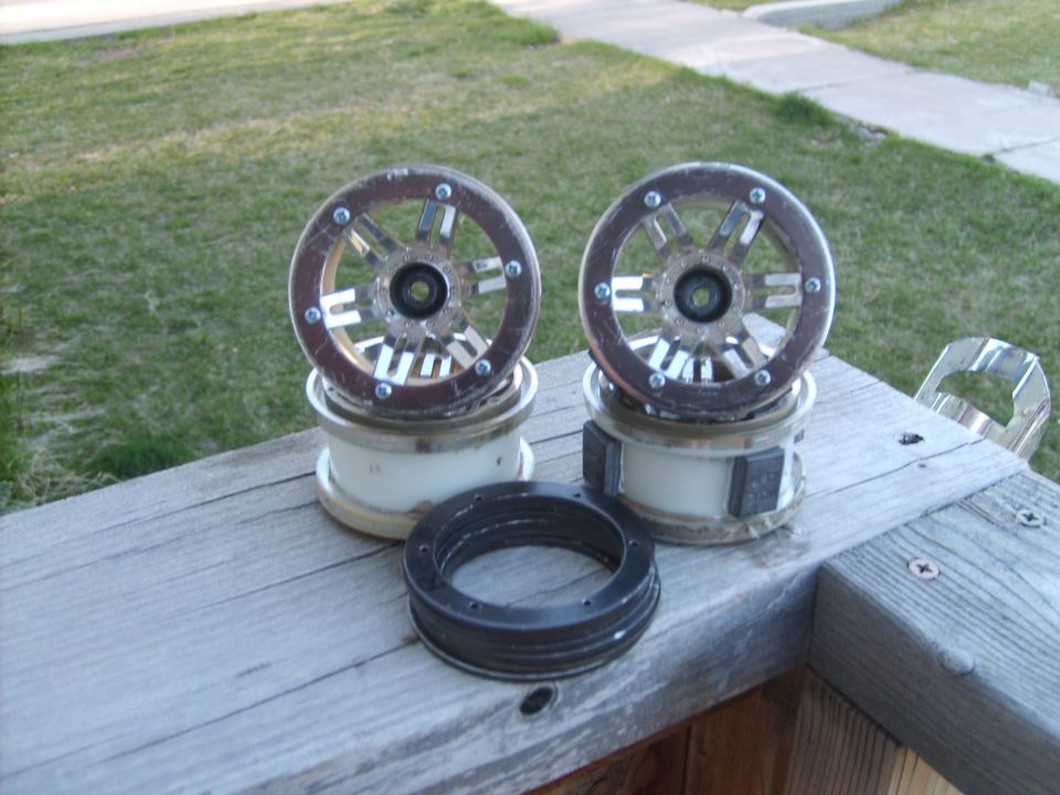 Two car wheel hubs stacked on top of what appear to be brake rotors, with another rotor in front. They are sitting on a wooden surface outdoors