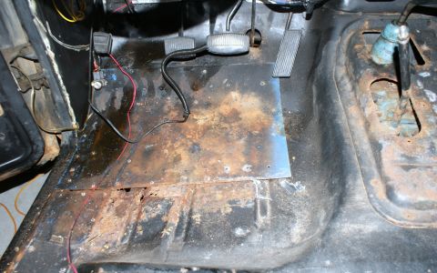 1979 Ford Bronco - The interior floor of a vehicle shows significant rust damage and exposed metal panels.