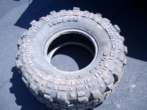 1979 Ford Bronco - A Super Swamper TSL/SX tire is shown resting on asphalt.