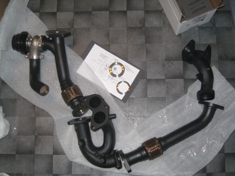 2007 Subaru Impreza - Automotive exhaust parts laid out on a checkered floor, including a wastegate and manifold with braided sections.