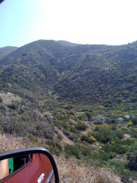 1978 Ford Bronco - A scenic view of a waterfall in a mountainous region, seen from the perspective of a moving vehicle.