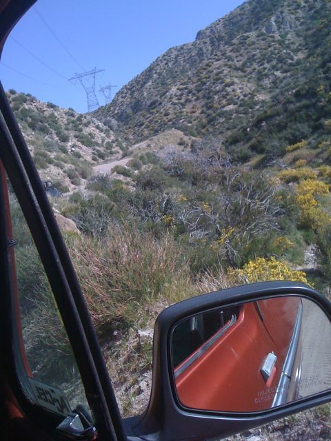 1978 Ford Bronco - View from inside an orange vehicle, reflecting a mountainous terrain in the side mirror.