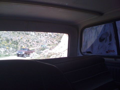 1978 Ford Bronco - Interior perspective shows a brown pickup truck on a dirt road, with another vehicle in the distance.