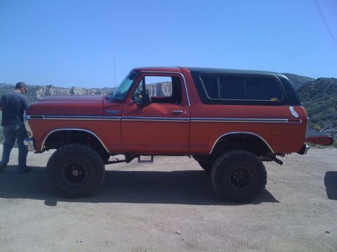 1978 Ford Bronco - This 1978 Ford Bronco is shown in profile, a red body, black hardtop, and lifted suspension with oversized wheels.