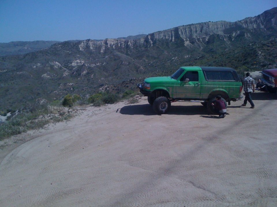 Green SUV with lifted suspension and aftermarket wheels parked on a dirt road