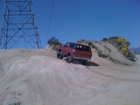 1978 Ford Bronco - 1978 Ford Bronco tackling an off-road trail near a large power line tower.