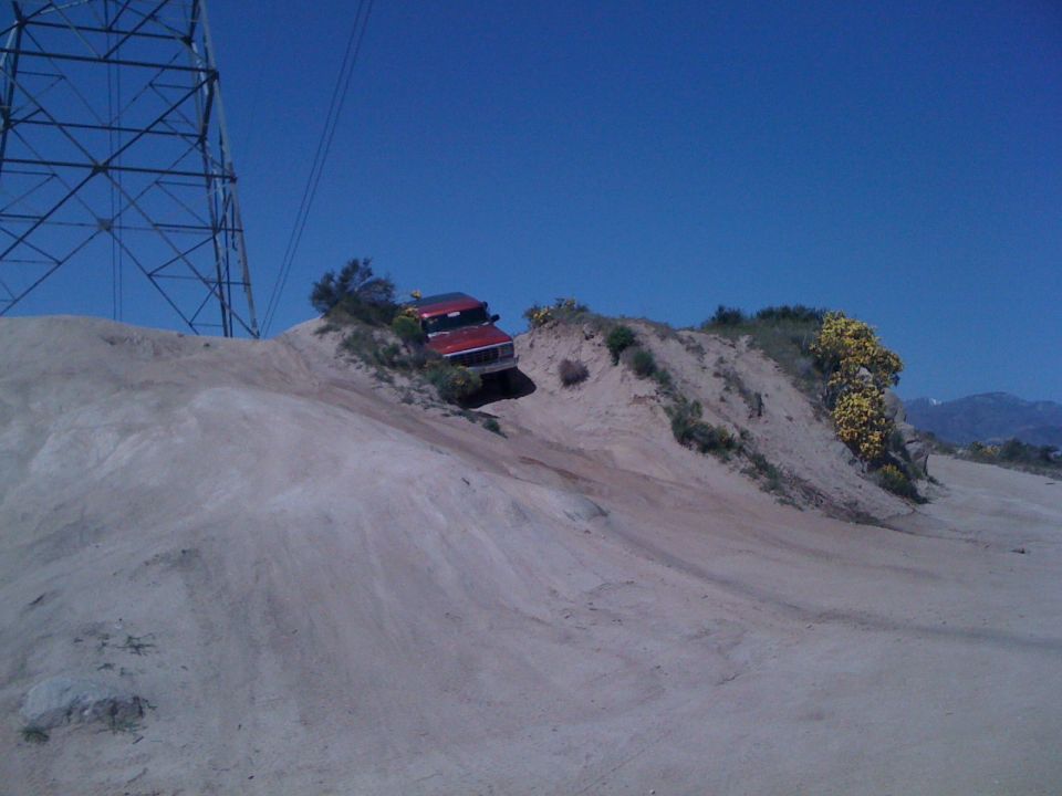 Red 1978 Ford Bronco driving on a dirt hill