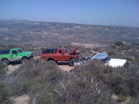 1978 Ford Bronco - Several off-road vehicles are gathered in a , arid terrain under a clear blue sky.