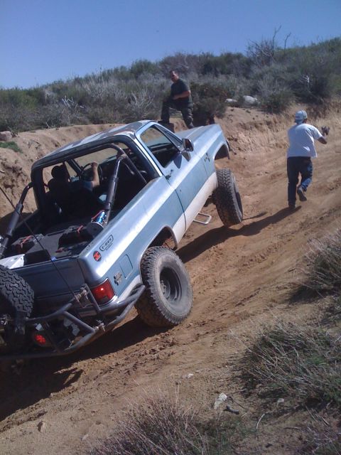 1978 Ford Bronco - Off-road truck navigating a steep dirt trail with two spectators present.