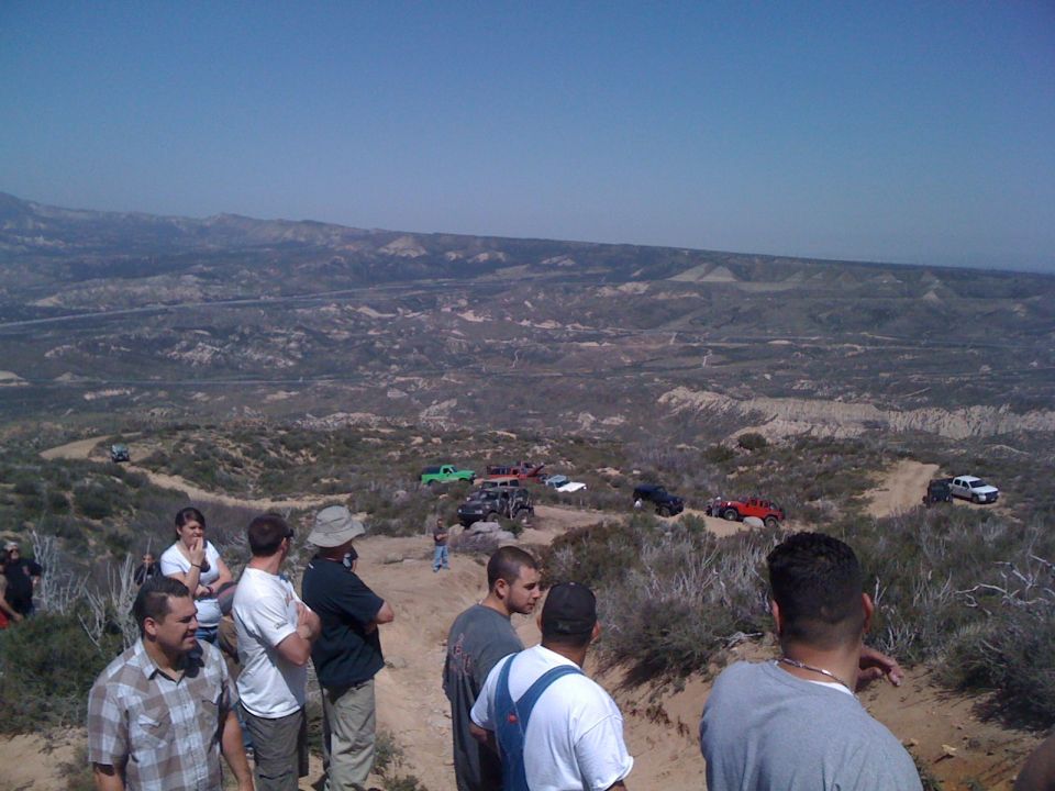 1978 Ford Bronco on a dirt trail with other off-road vehicles and people