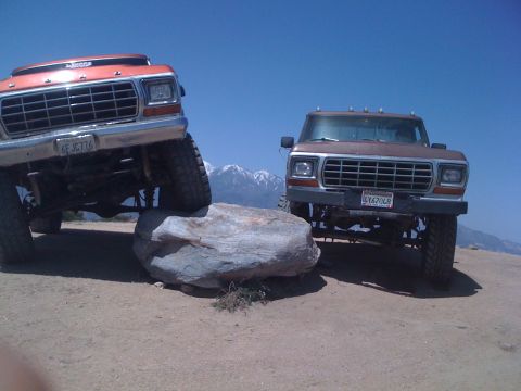 1978 Ford Bronco - Two modified trucks navigate a rocky landscape under a clear blue sky.