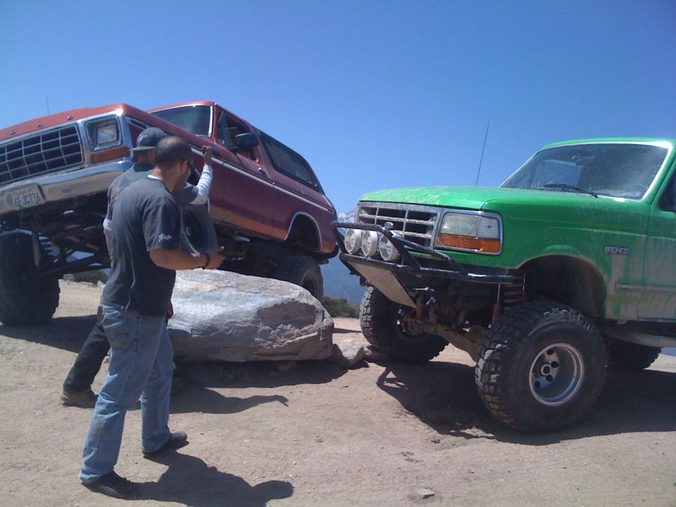 Green Ford Bronco and a red Ford Bronco on rocks