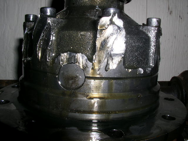 Damaged differential housing with visible metal deformation and oil