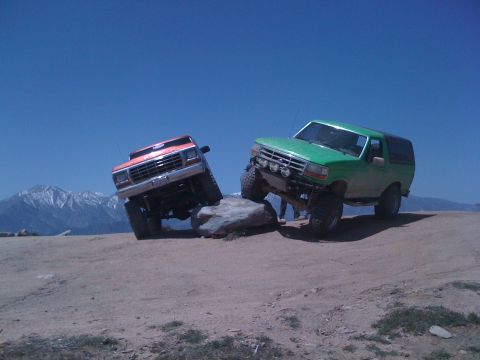 1978 Ford Bronco - Two Ford Broncos navigate a rocky trail under a clear blue sky.