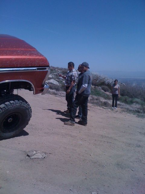 1978 Ford Bronco - People gathered around an orange 1978 Ford Bronco on a dirt path with a scenic overlook in the background.