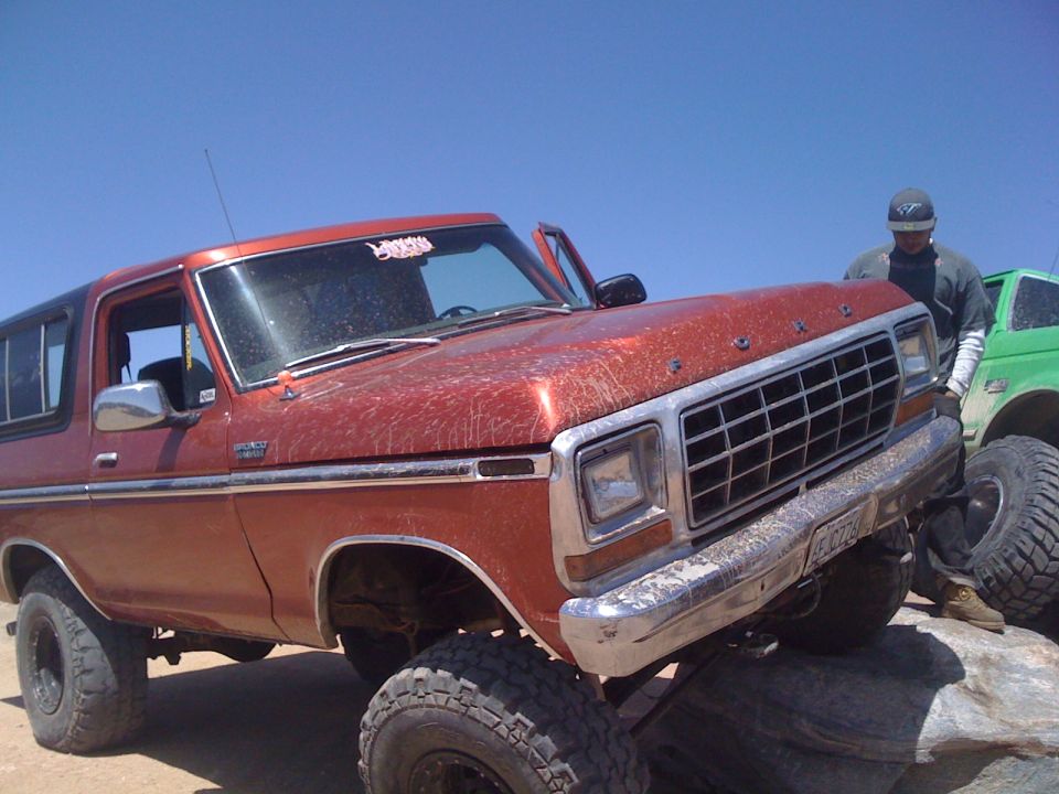 Orange 1978 Ford Bronco with lifted suspension on rocks