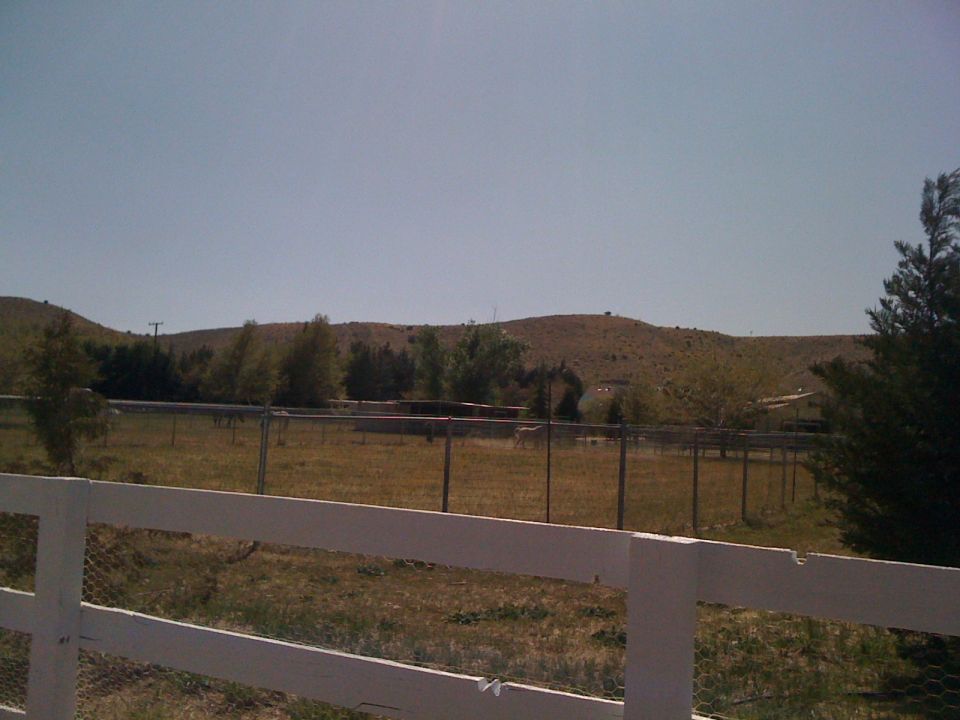 Rural landscape with white fence in foreground and distant hills under a clear sky