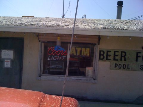 1978 Ford Bronco - A building with a neon Coors Light sign and an ATM machine visible through the window.