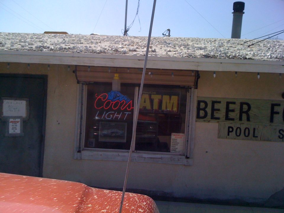 Building with Coors Light and ATM signs in window. Beer For Pool sign on side