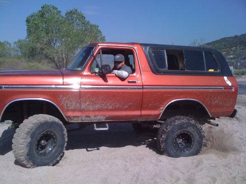 1978 Ford Bronco - This lifted 1978 Ford Bronco is shown in profile, navigating sandy terrain with its large off-road tires.