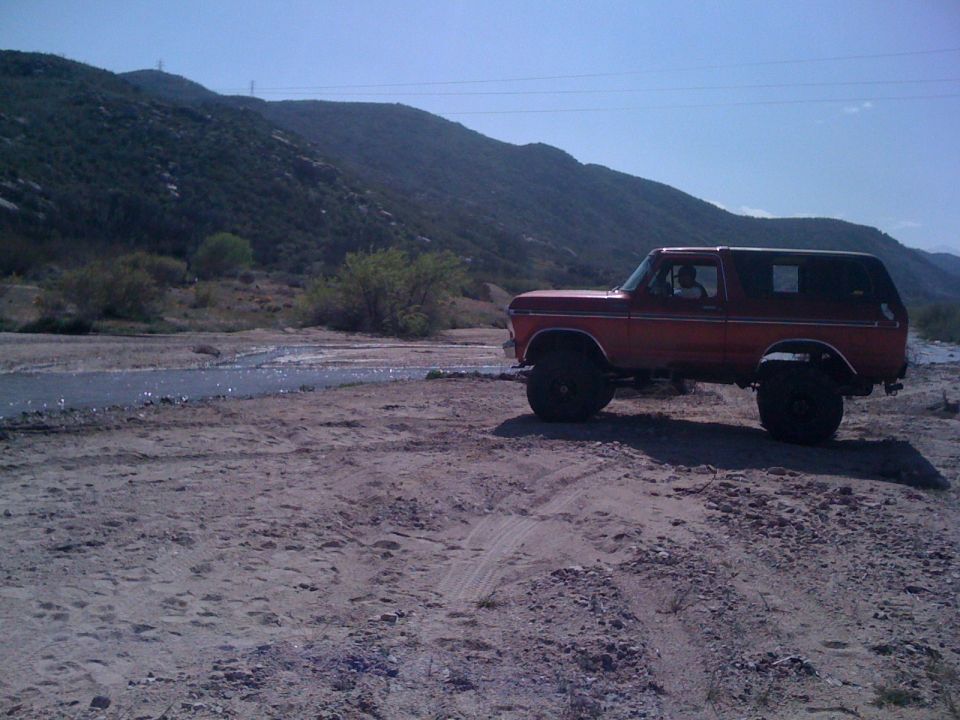 Orange 1978 Ford Bronco parked on dirt, side view