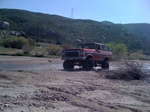 1978 Ford Bronco - 1978 Ford Bronco navigating a water crossing in a , natural landscape.