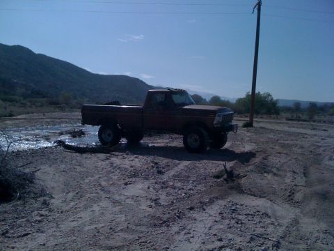 1978 Ford Bronco - A lifted Ford F-Series truck sits in a dry, dusty landscape with mountains in the background.