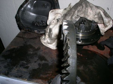 1979 Ford Bronco - A severely damaged ring gear and differential assembly are shown on a messy workbench, indicating a mechanical failure.