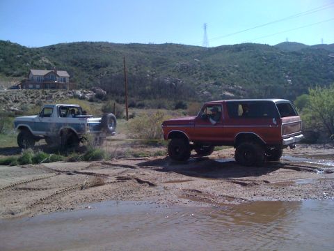1978 Ford Bronco - Two Ford Broncos tackle rough terrain, one assisting the other with a tow strap.