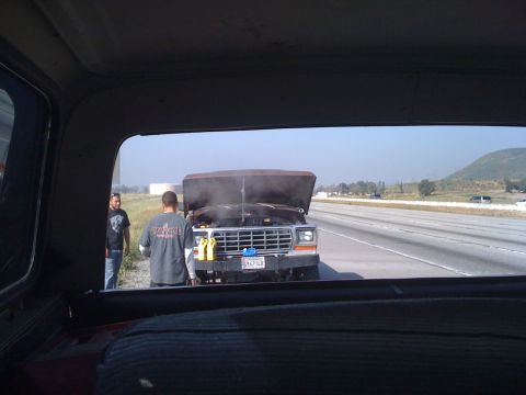 1978 Ford Bronco - Ford F-Series truck with hood open on highway, possibly overheating, with two men attending to it.