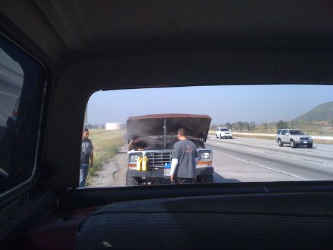 1978 Ford Bronco - A truck appears to be broken down on the side of the highway with steam rising from the engine.