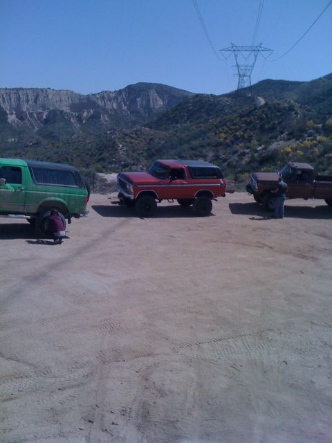 1978 Ford Bronco - Three SUVs and a pickup truck are parked on a dirt lot with mountains in the background.