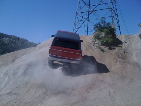 1978 Ford Bronco - 1978 Ford Bronco tackling an off-road trail with dust kicking up.