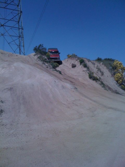 1978 Ford Bronco - An orange SUV is parked on a sandy hill under a clear blue sky.